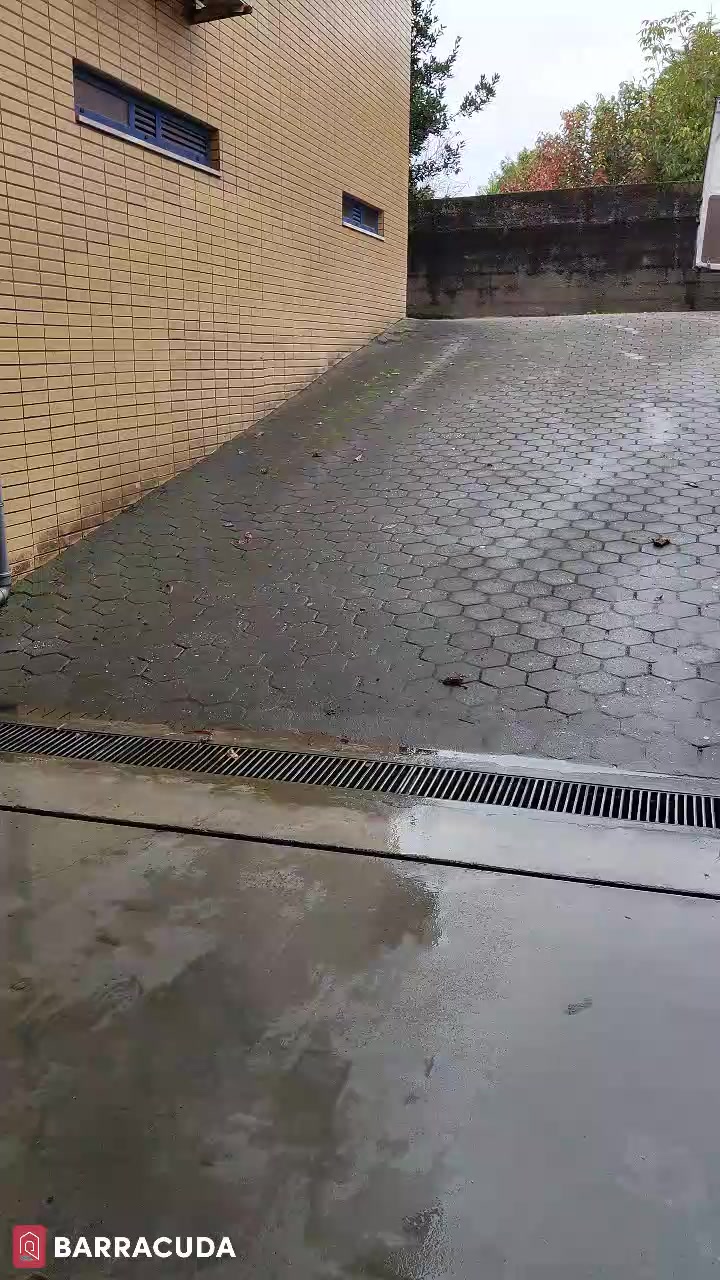 Rampa de acesso lavada, com a água a escoar para o ralo